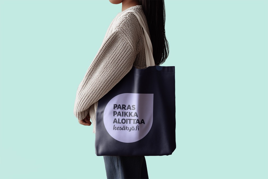 Pitkähiuksinen henkilö pitää olallaan kangaskassia, jossa on Paras paikka aloittaa -tunnus.